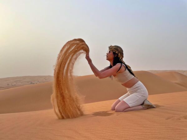 Tourist posing on sand dunes on the desert safari trip 2022 Dec