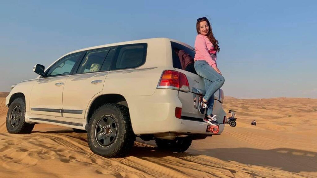 Tourist standing with the jeep at desert safari tour